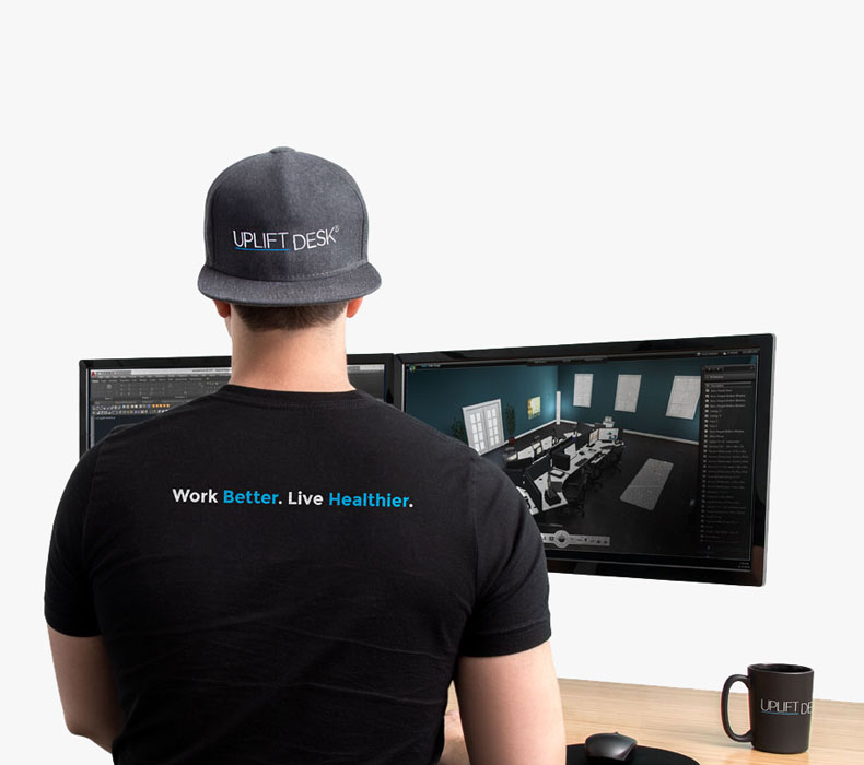 Employee at workstation in UPLIFT Desk branded apparel featuring 'Work Better. Live Healthier' slogan on t-shirt.