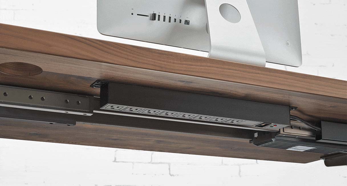 An 8-Outlet Mountable Surge Protector mounted to a desktop with outlets facing down
