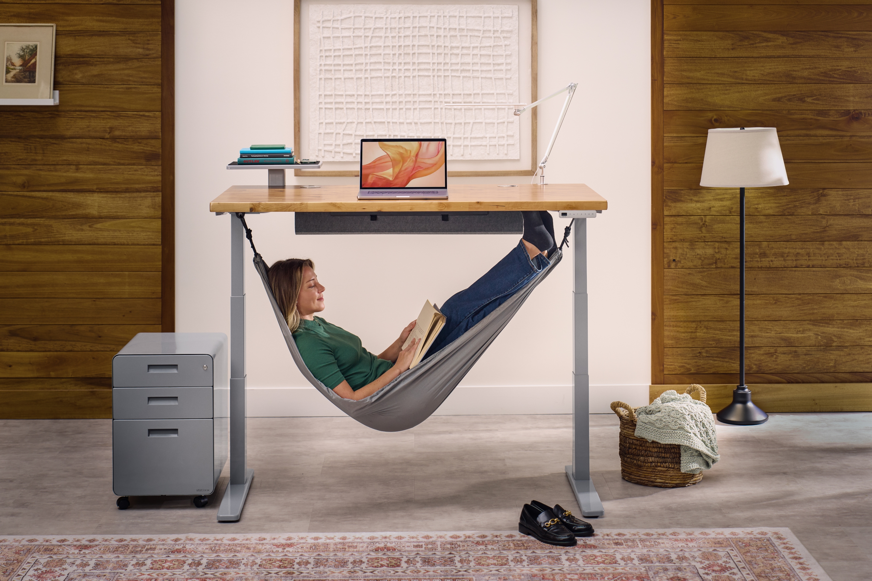 Person sitting in an Under Desk Hammock attached to the Uplift Standing Desk using included Anchor Plates.