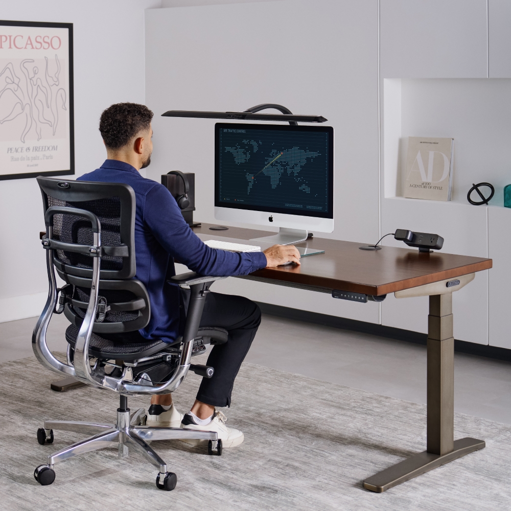 Person sitting an UPLIFT V3 Standing Desk doing office work