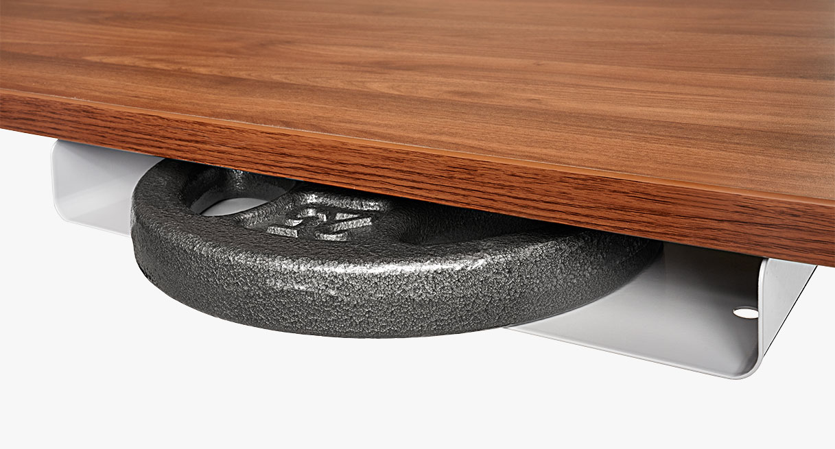 The slim desk shelf with a weight plate inside attached to a standing desk