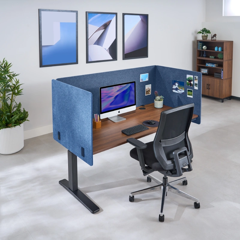 3-Sided Tall Acoustic Privacy Panels in Dark Blue attached to an UPLIFT Standing Desk decorated with post cards for personalization