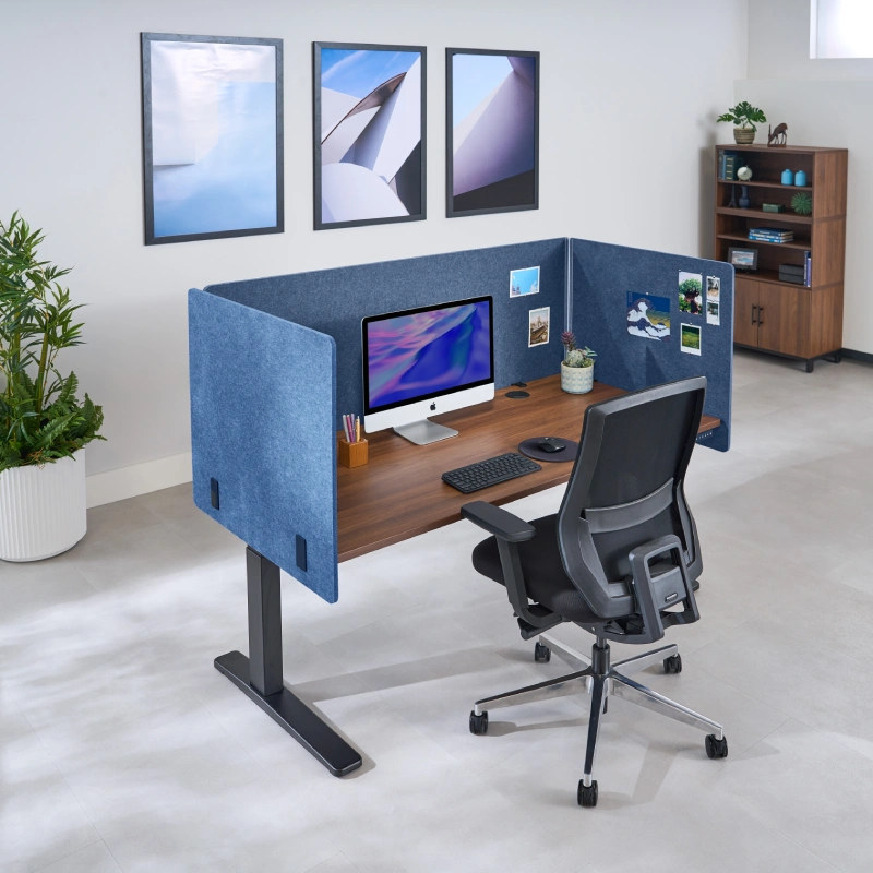 3-Sided Tall Acoustic Privacy Panels in Dark Blue attached to an UPLIFT Standing Desk decorated with post cards for personalization