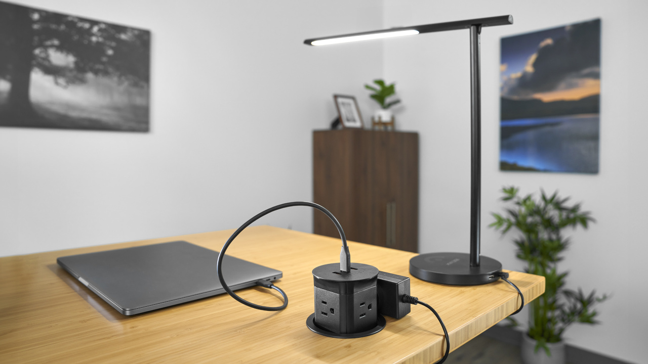 Black Pop Up Power Grommet with a laptop and desk lamp plugged into it.