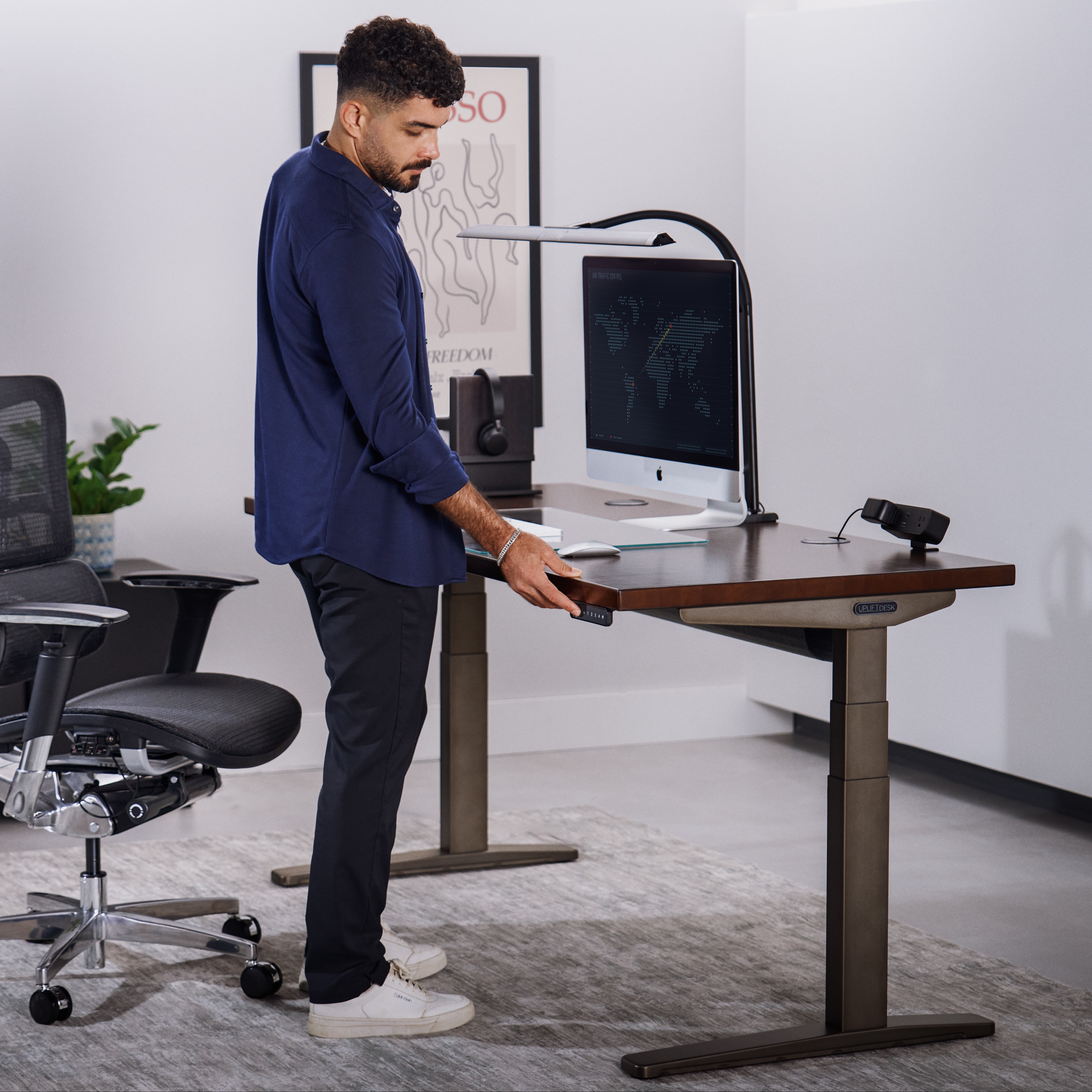 Person standing at an Uplift Standing Desk pushing a keypad button