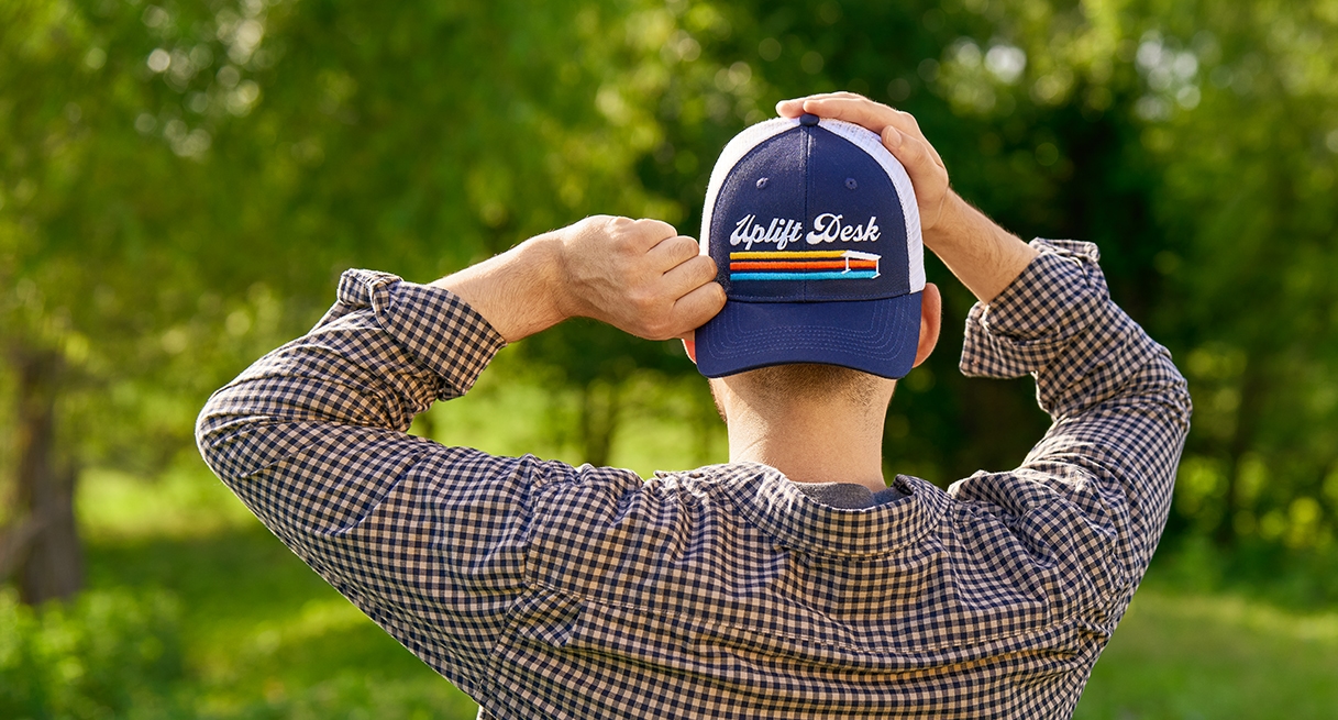 Man placing an UPLIFT Desk Cap on his head backward