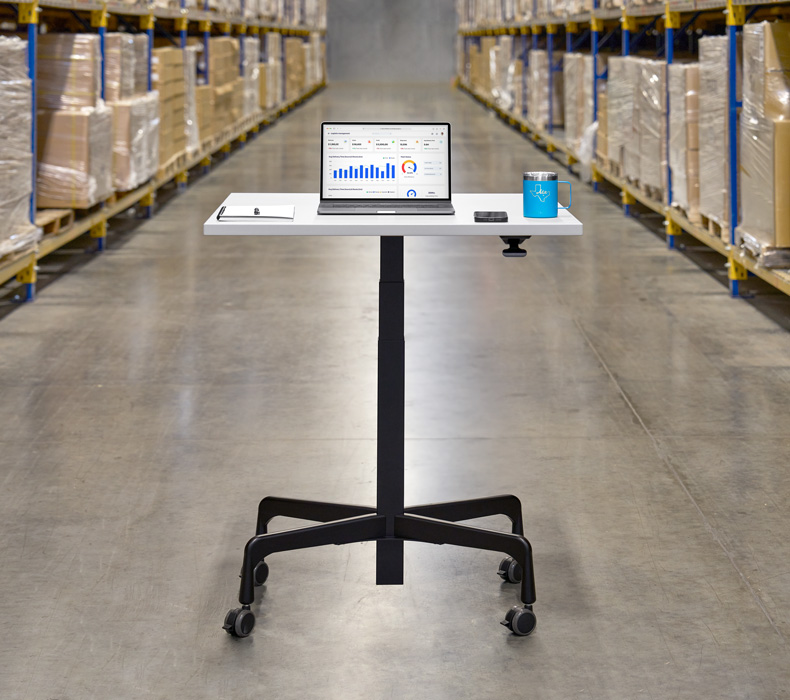 An ergonomic UPLIFT Height Adjustable Bistro Table with casters in a warehouse