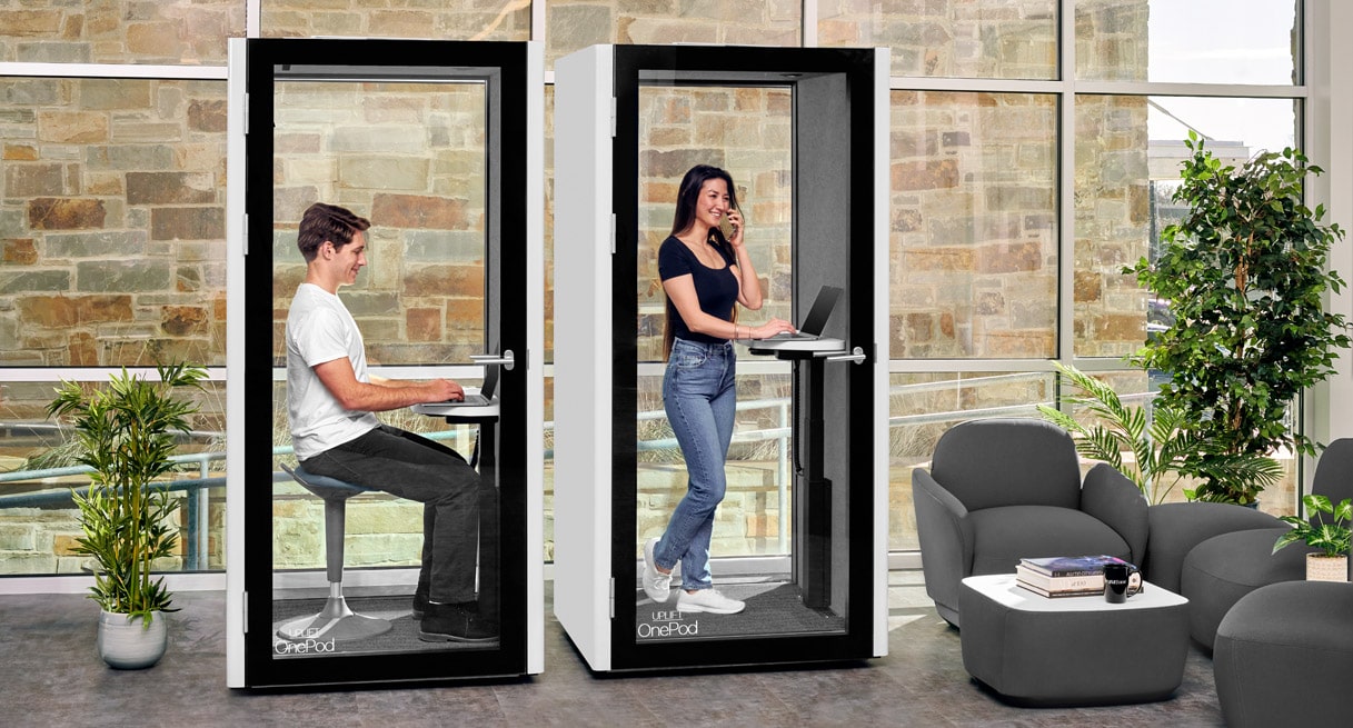 Two people working in separate OnePod Office Phone Booths, one standing and one sitting