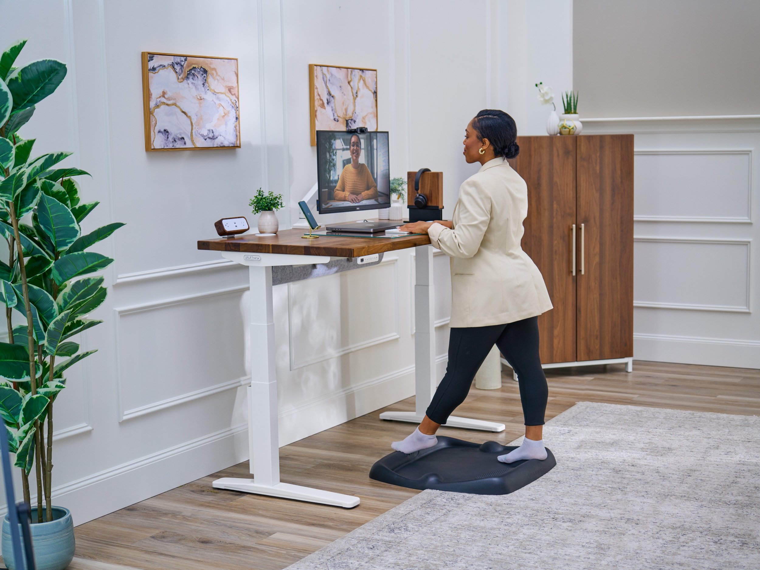 Woman standing on top of an ant-fatigue standing mat at a V3 2-leg standing desk next to a mopac wardrobe