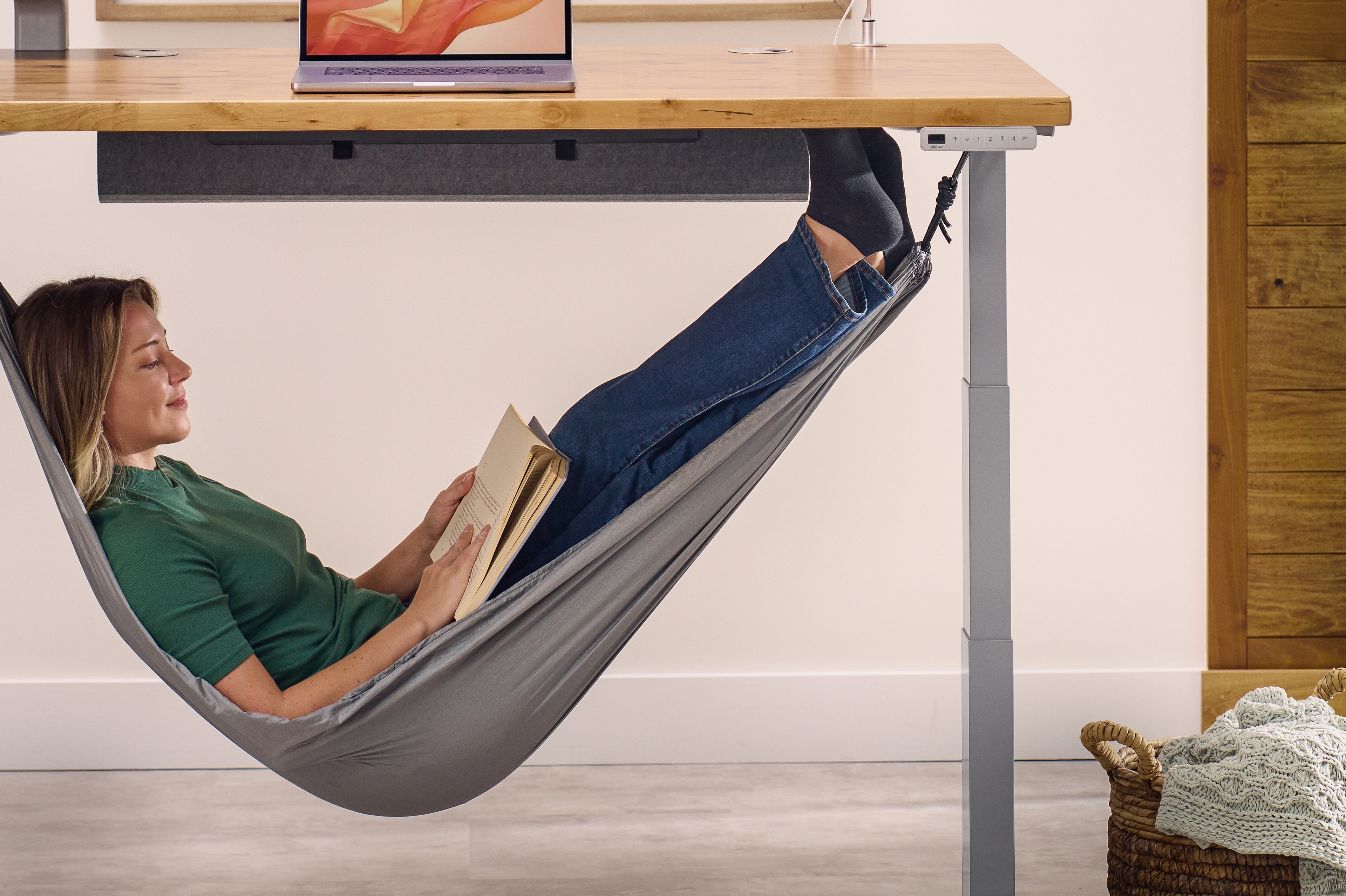 Person laying in an under-desk hammock reading