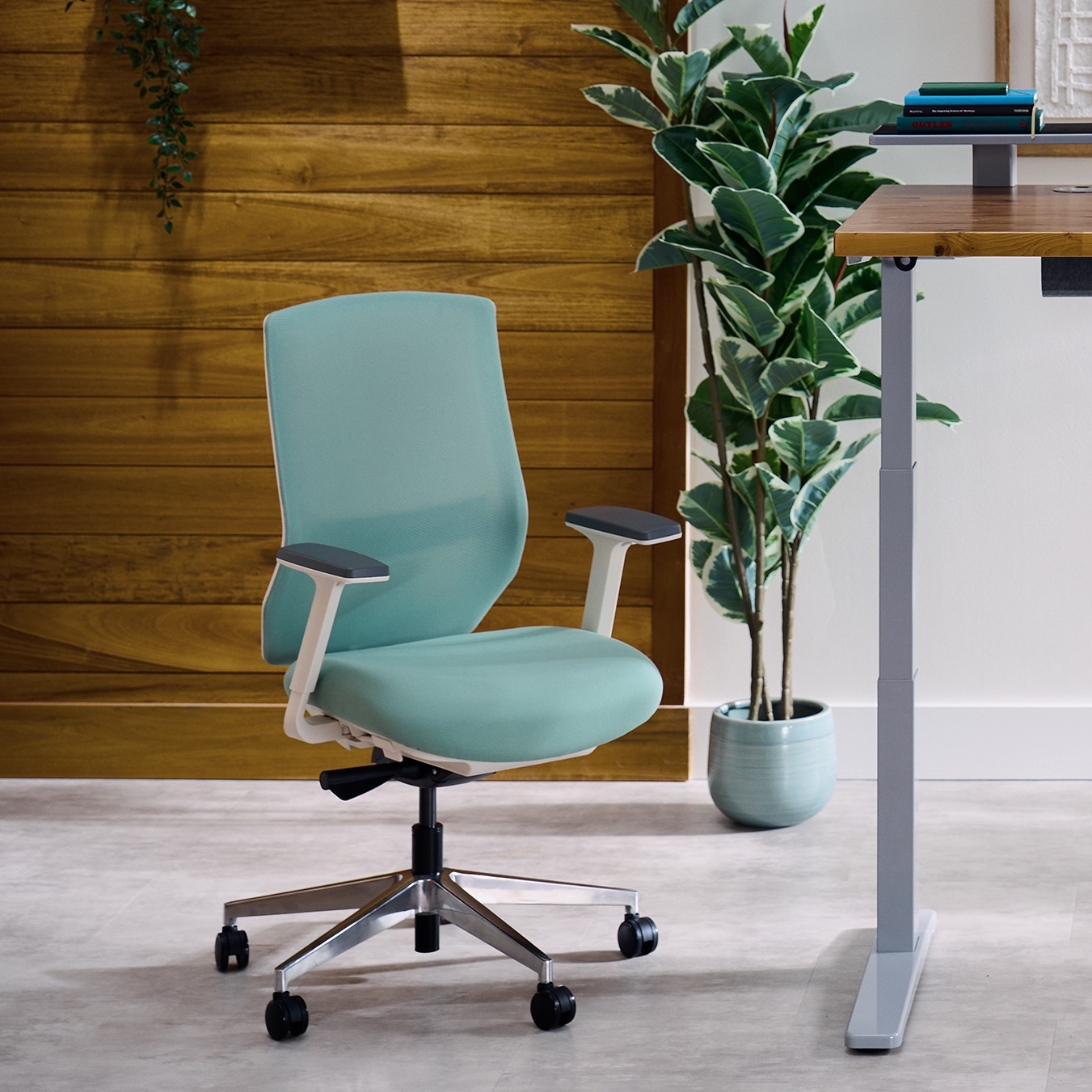 Envoke ergonomic chair in sage next to an Uplift standing desk.