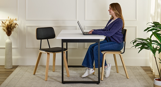 A young-woman seated working on a laptop seated in a Kerbey Chair by UPLIFT Desk