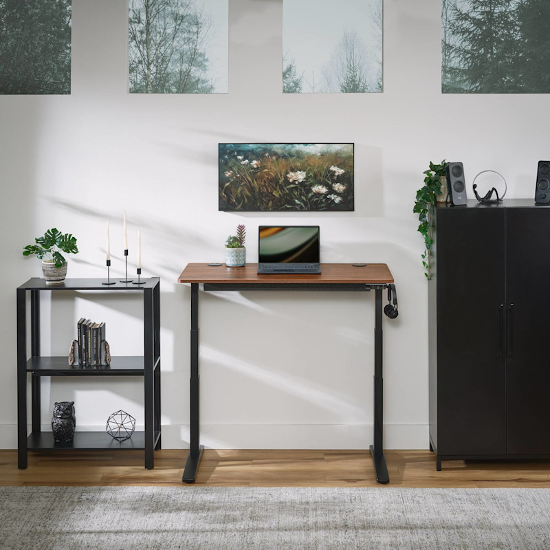 UPLIFT V3 Essential Standing Desk in a small home office paired with Sequence Shelves and a MoPac Wardrobe in black
