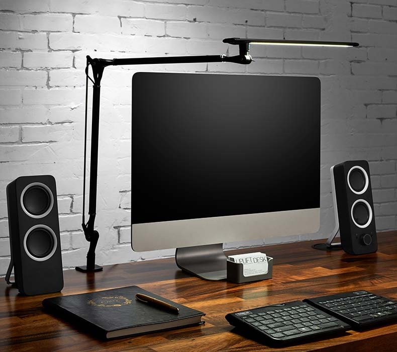 A black LED Desk Lamp E7 clamped to the back of a Saman Butcher Block Solid Wood UPLIFT Standing Desk