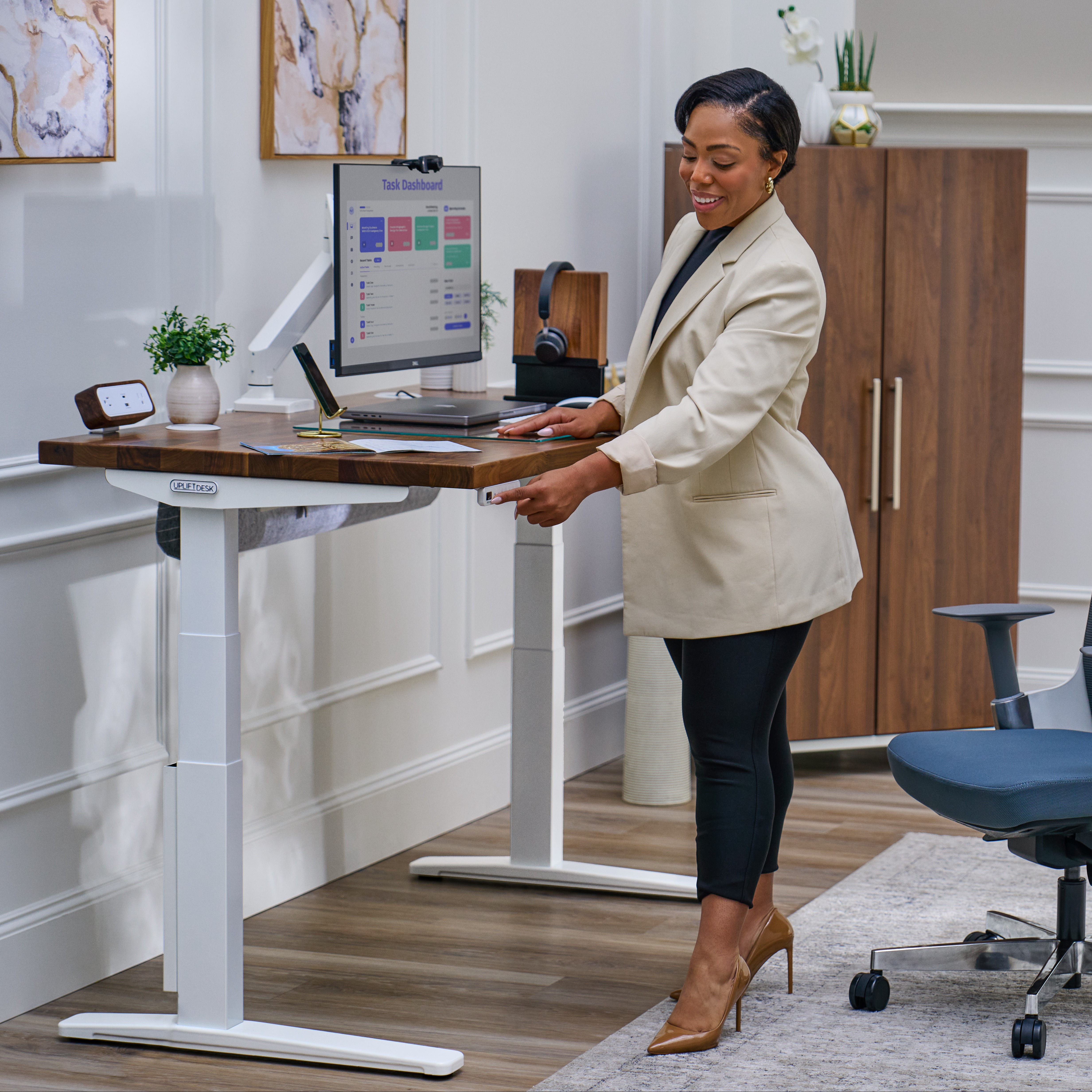 Person standing at Uplift Standing Desk pressing a keypad button and smiling.