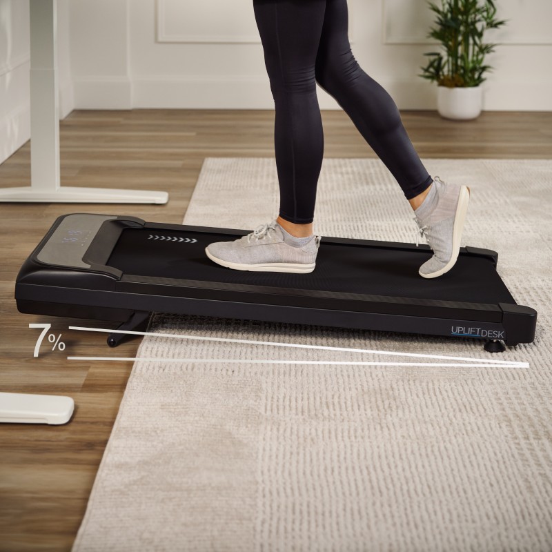 Person using a walking pad while working at a height-adjustable desk