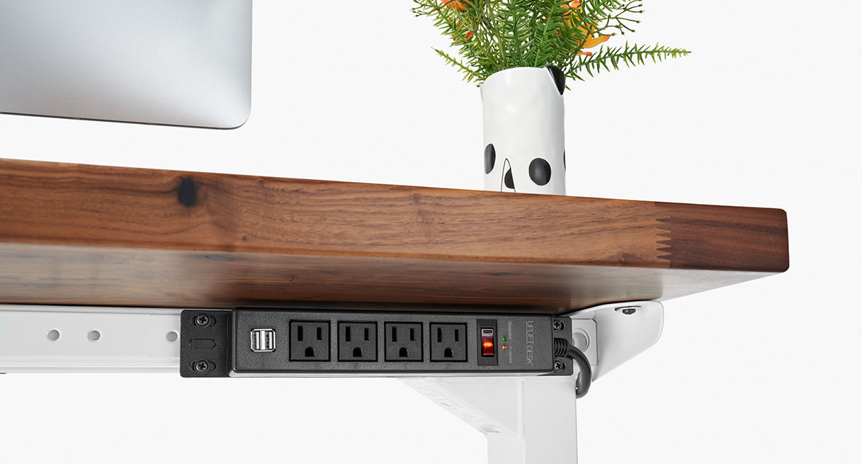 A 4-outlet power strip mounted to the rear patented UPLIFT height adjustable desk accessory mounting holes