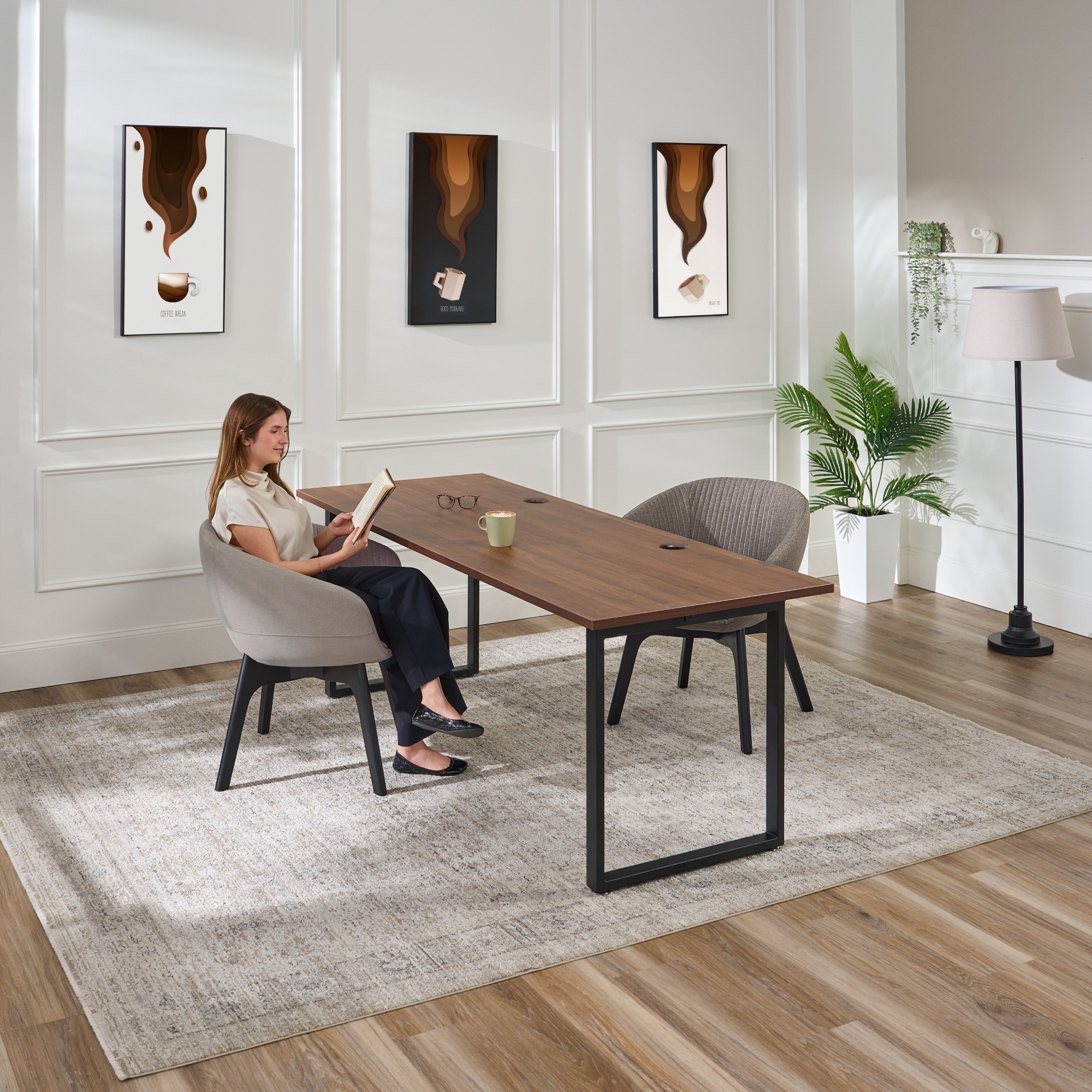 Person reading comfortably seated in a Rivervue Arm Chair in Slate at an Seated Height O-Leg Table by UPLIFT Desk