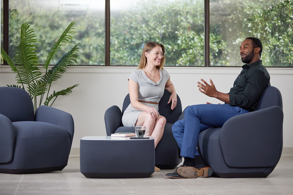 Two people sitting in a Dillo Lounge configuration chatting.