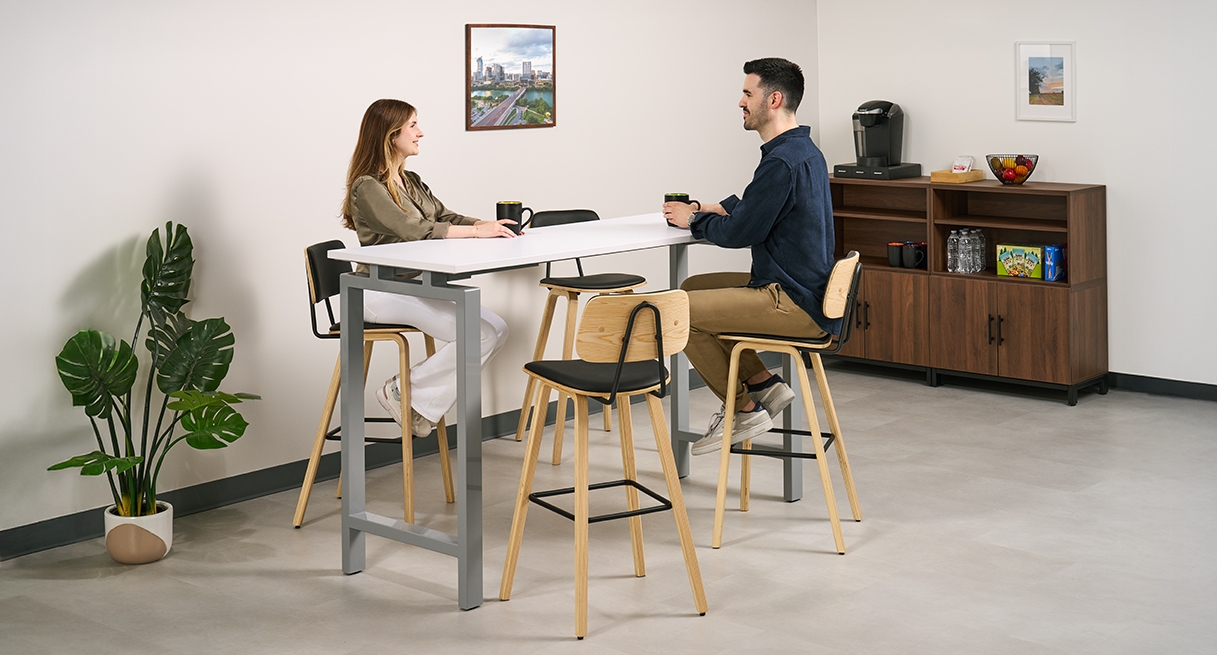 Two office workers conversing, seated in Kerbey Barstools by UPLIFT Desk