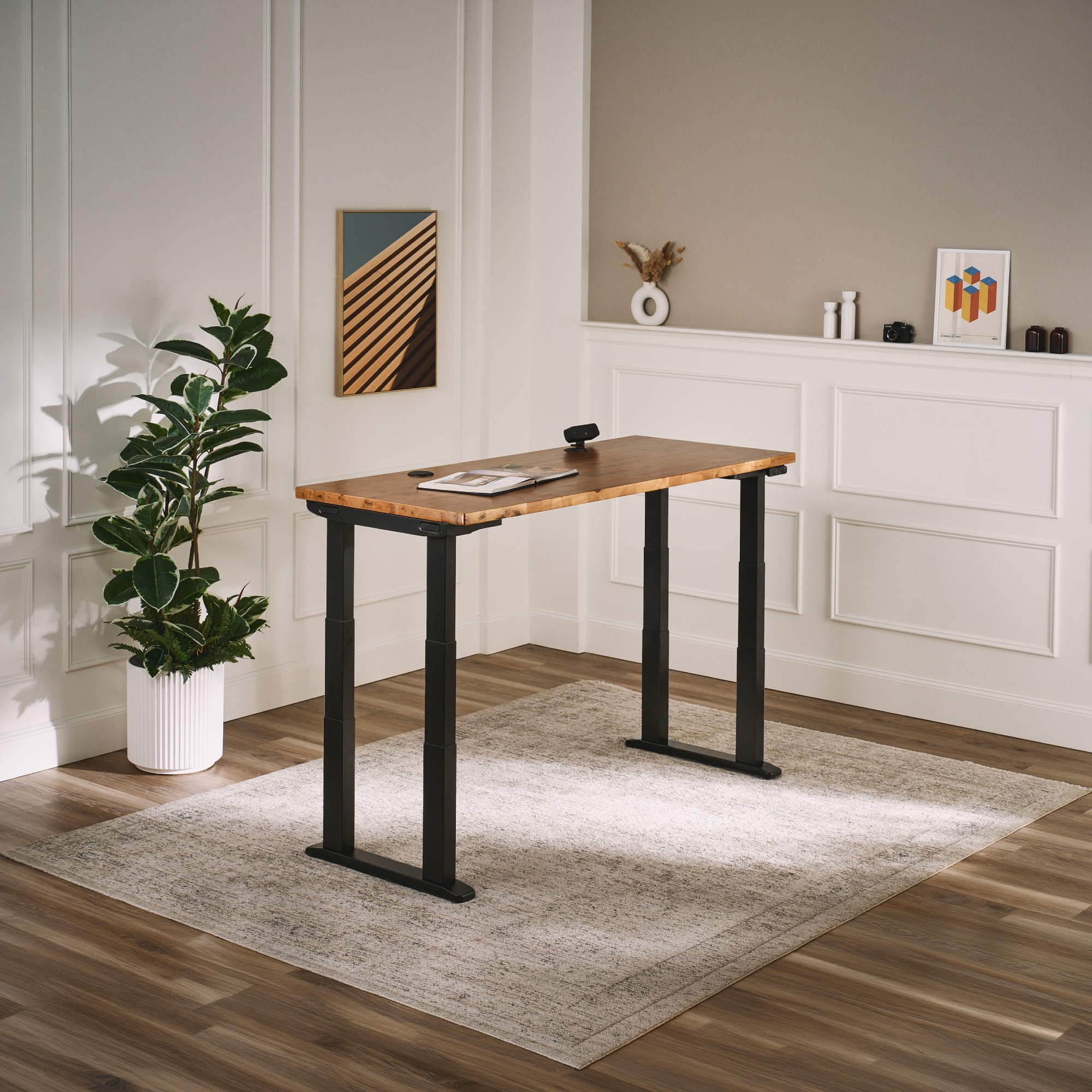 UPLIFT V3 4-Leg Standing Desk with black frame and solid wood desktop set to standing height in a small home office