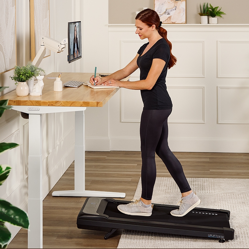 Person walking on a walking pad working at an Uplift Standing Desk.