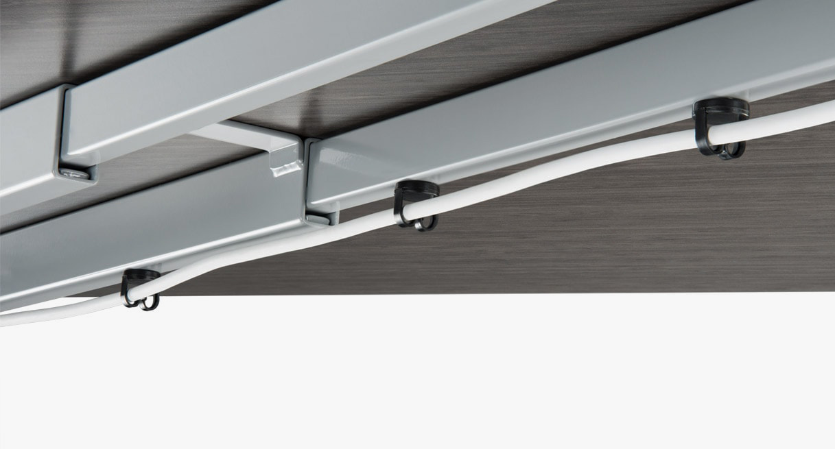 Magnetic wire management cable clips attached to a standing desk frame with a cable routed through them