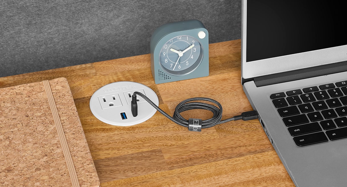 A Power Grommet with USB charging a laptop on an UPLIFT Standing Desk