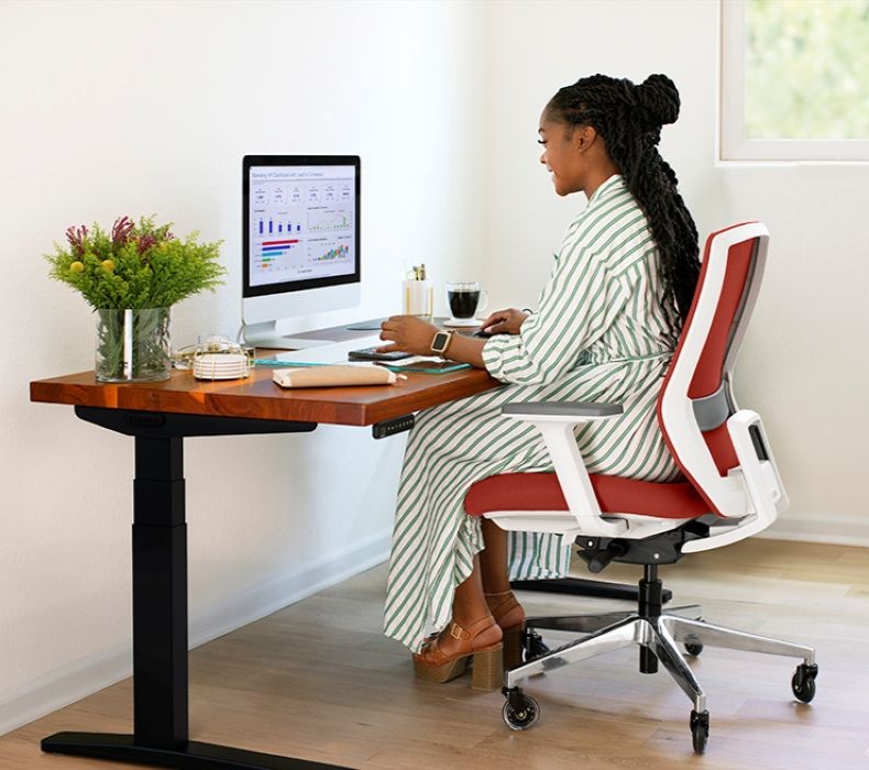 A woman in a stylish office chair working productively at a desk, demonstrating proper posture and comfort.
