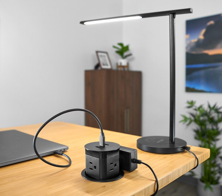 Pop-up Power Grommet by UPLIFT Desk, shown in black, features four 120V grounded power outlets, and two USB-A and one PD20W USB-C ports on top.