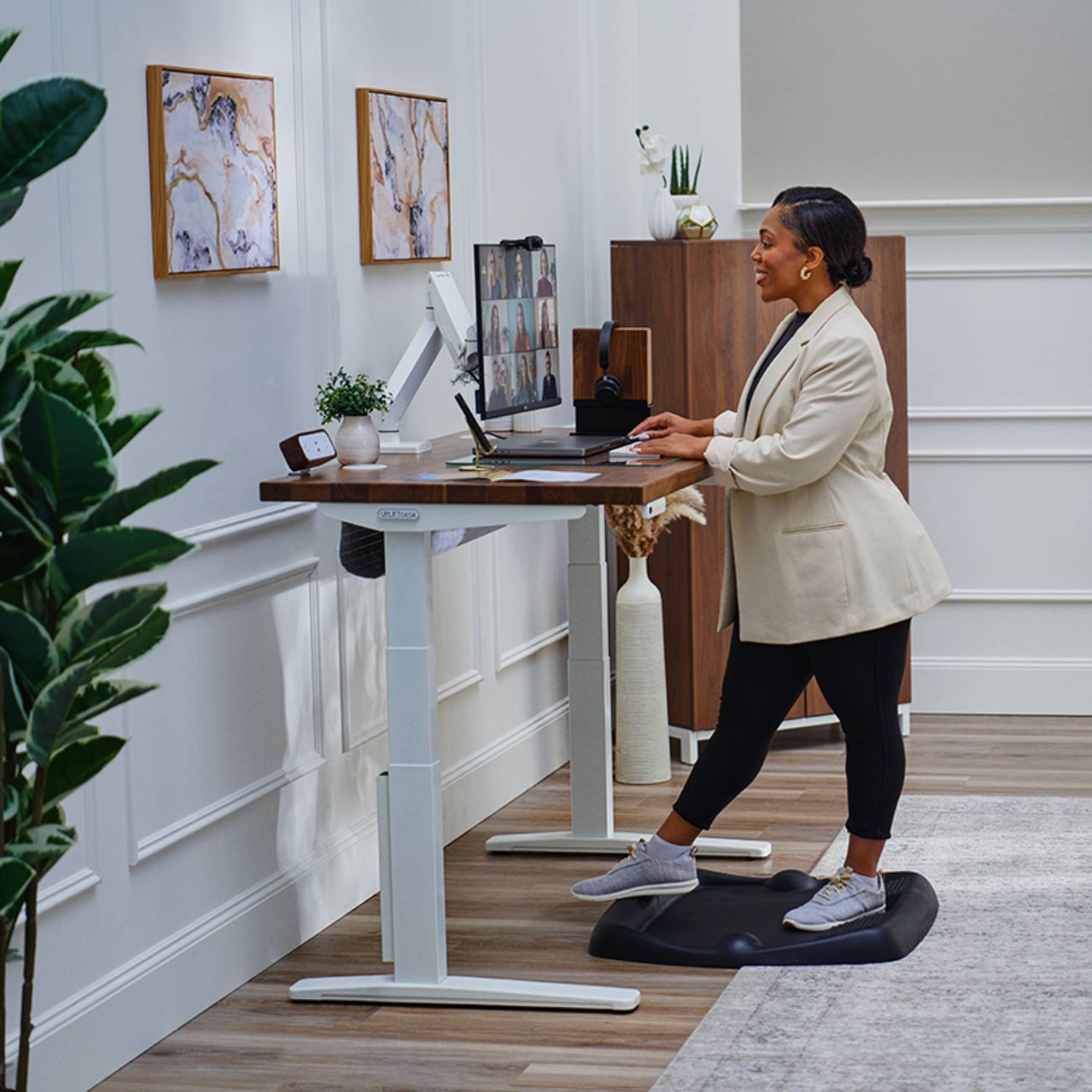 Person standing and working at an UPLIFT Height Adjustable Desk, utilizing the UPLIFT Desk App