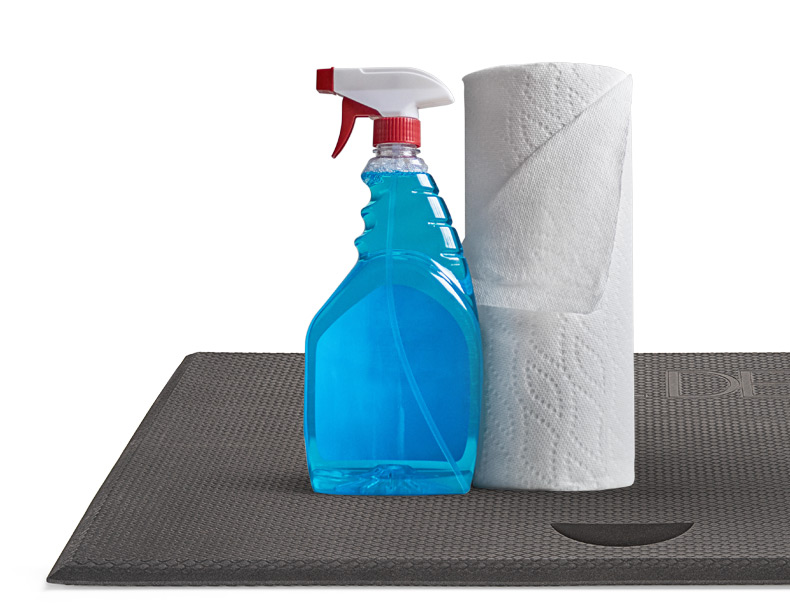 Cleaning supplies on top of the standing desk mat
