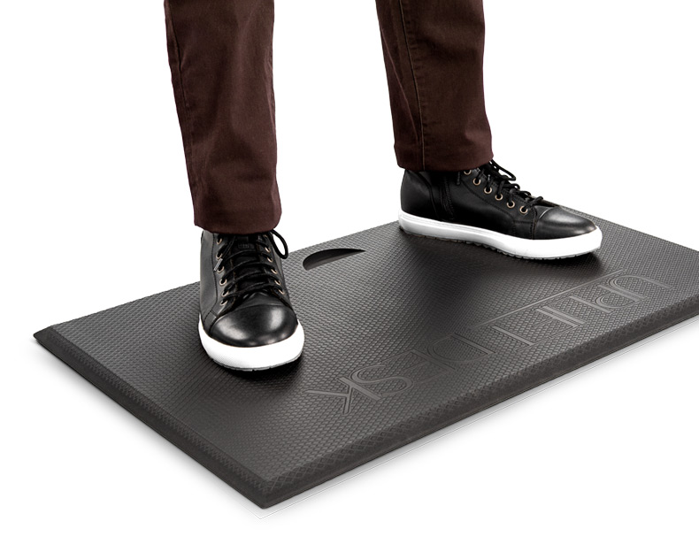Someone standing on the Standing Desk Mat with Heel grab