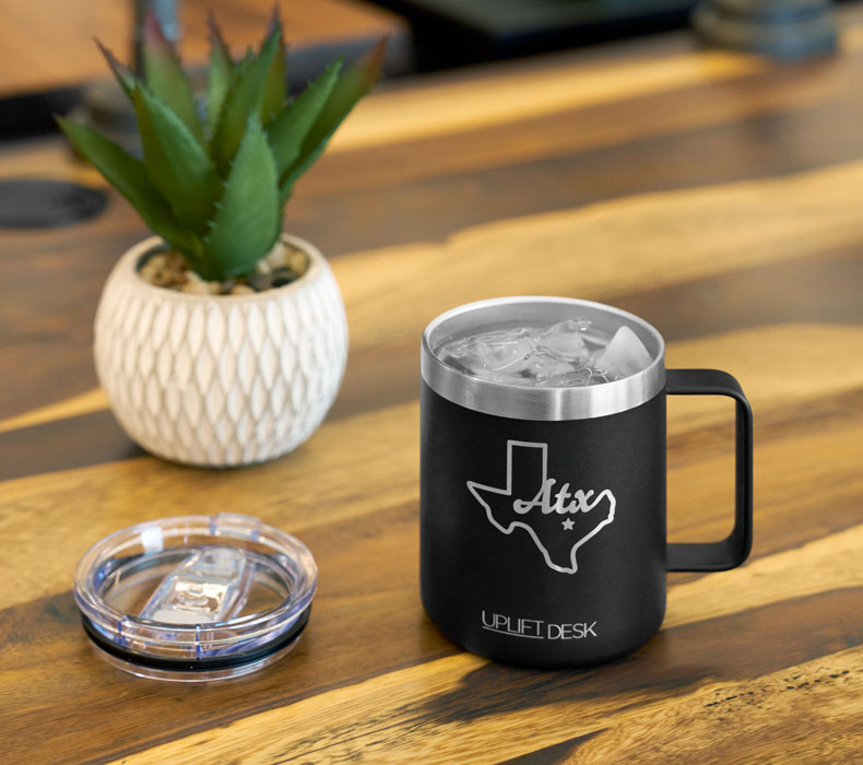 A close-up of a black insulated mug on top of a Pheasantwood Solid Wood Desktop