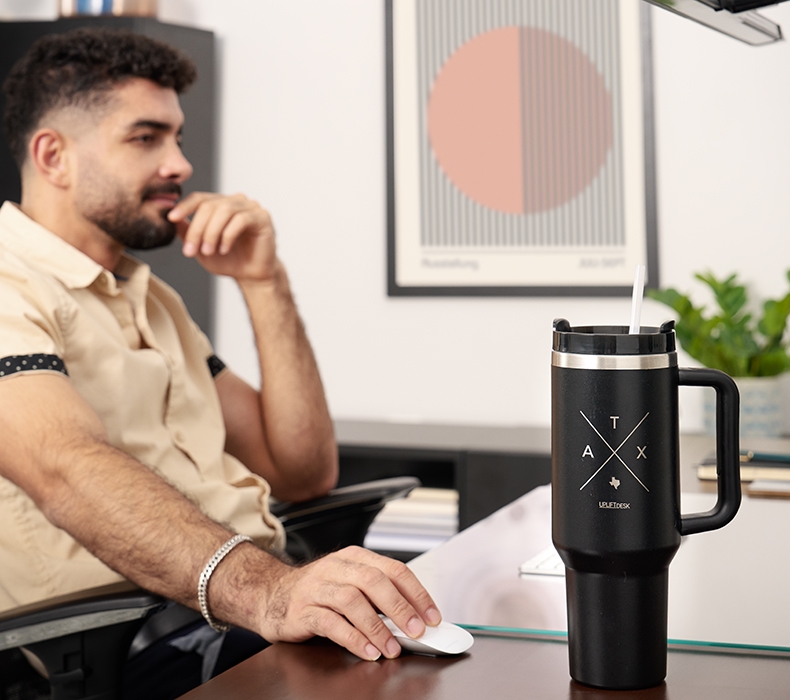 Man working at a desk, featuring a 40 oz black Austin Tumbler by UPLIFT Desk