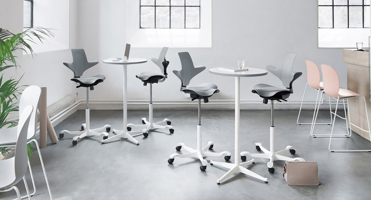 Light Gray Capisco Puls Chairs with white bases and stool cylinders raised up for use with standing height tables