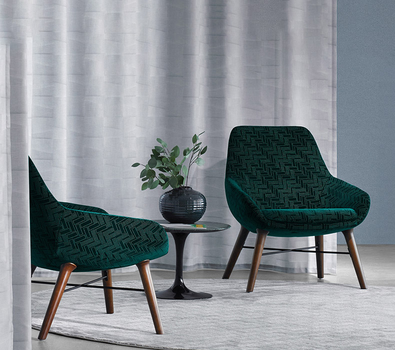 A lounge area with two emerald green Lilly Lounge Chairs with Walnut Wood Legs