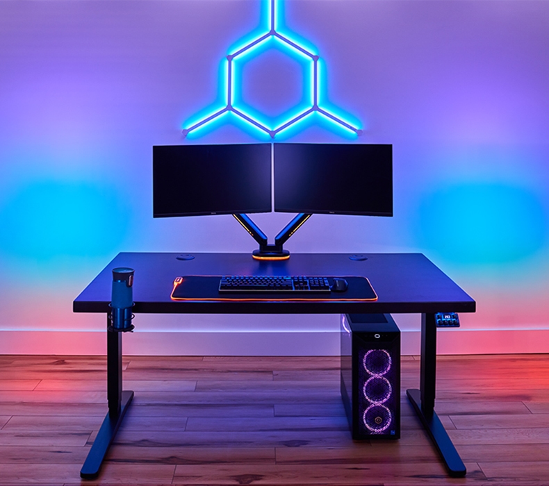 A black RGB Gaming keypad lit up and mounted to a standing desk with a black V2 frame