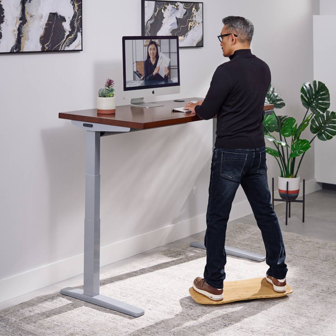 User on an UPLIFT Motion-X Board at a standing desk with a V3 XT Kit for an ergonomic, height-extended workstation