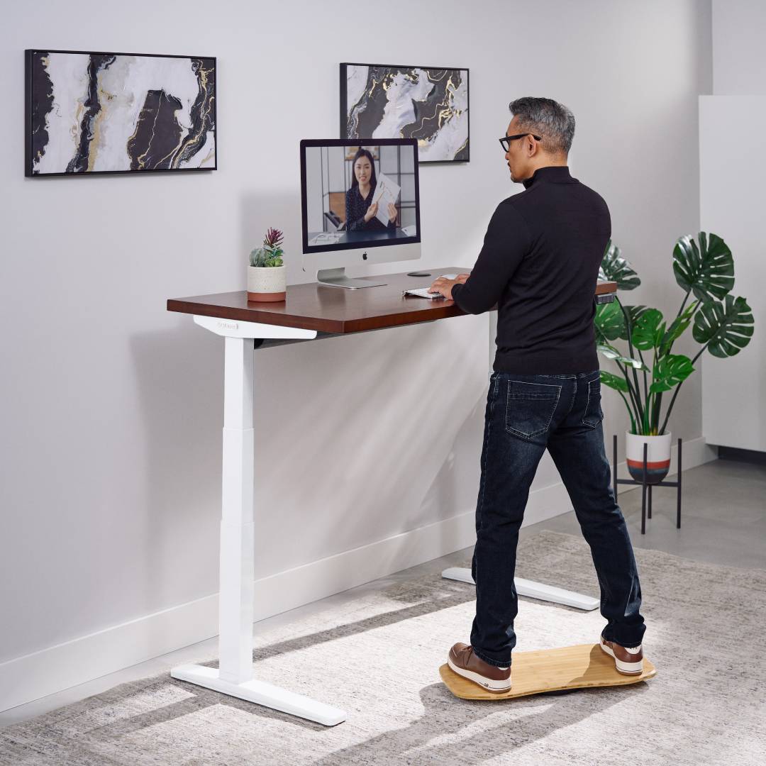 User on an UPLIFT Motion-X Board at a standing desk with a V3 XT Kit for an ergonomic, height-extended workstation