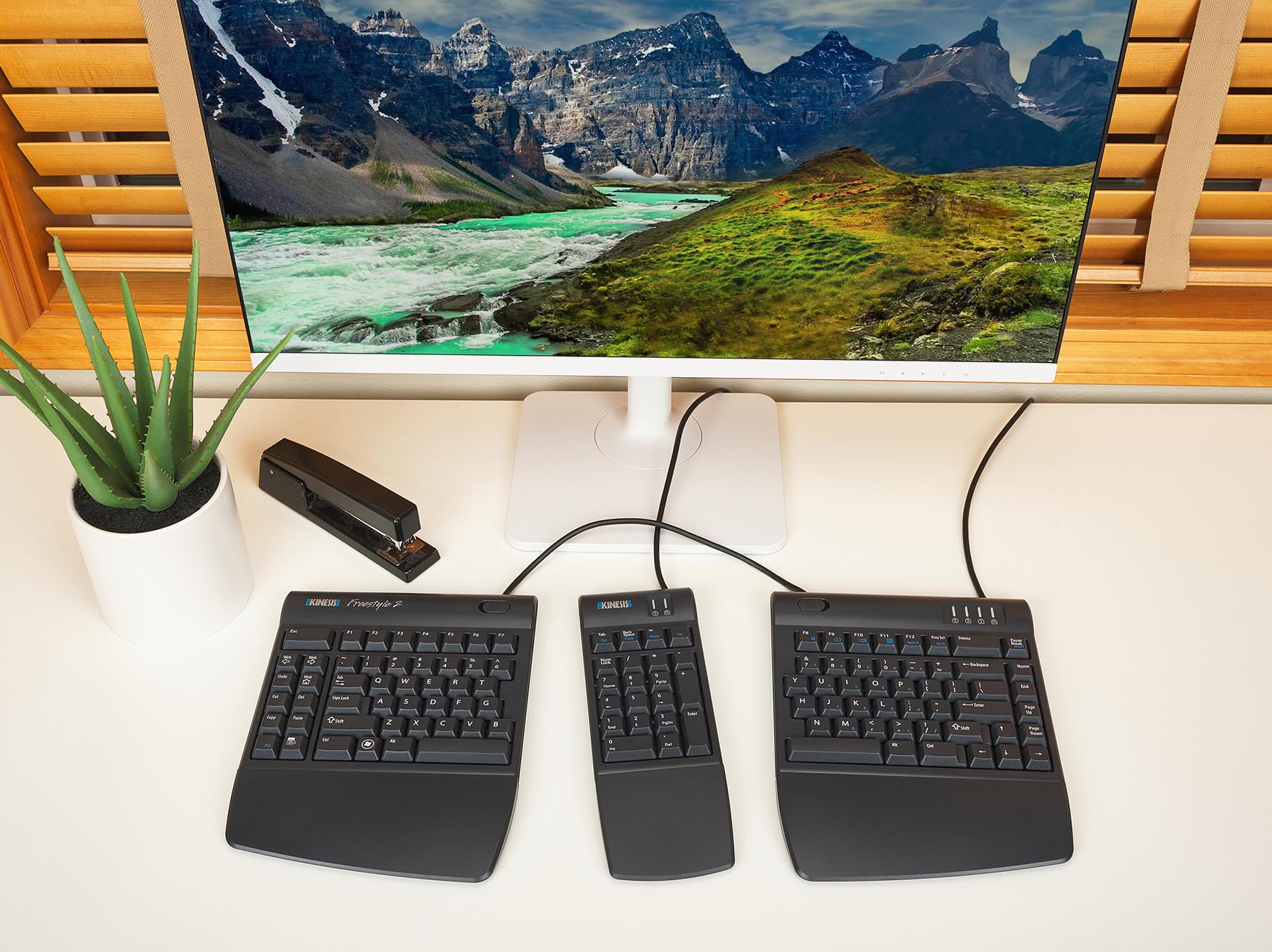 Desktop featuring a Kinesis Freestyle2 Numeric Keypad for PC with various desk items