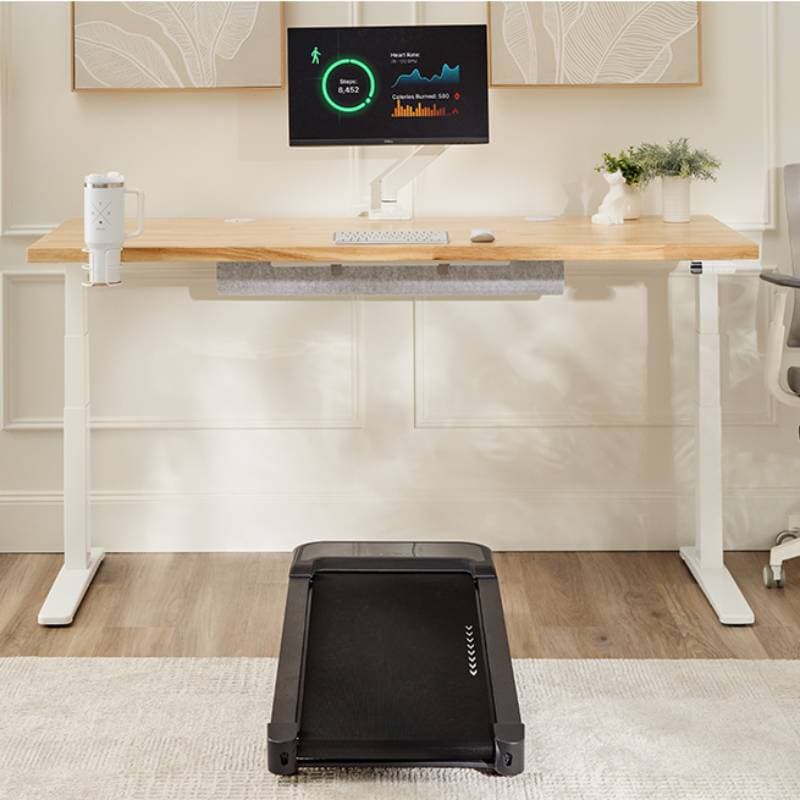 Black walking pad under a standing desk in a home office