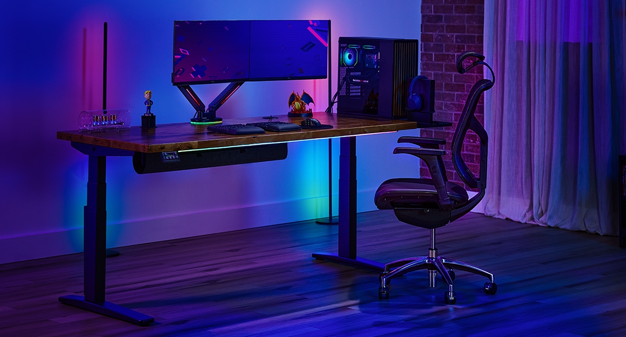 Uplift Standing Desk in Black with a Saman Butcher Block Desktop with RGB accessories for a gaming vibe.