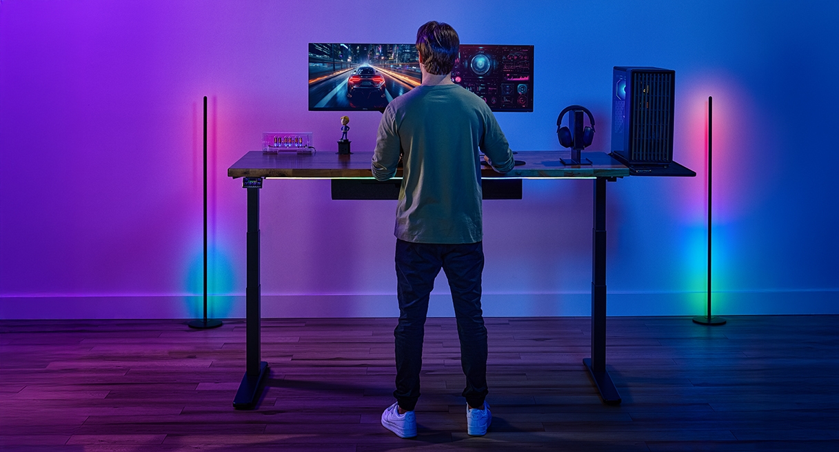 Person standing and gaming at an Uplift Standing Desk in Black with a Saman Butcher Block Desktop.