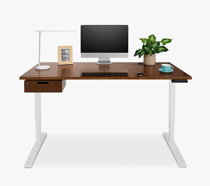 A standing desk with a drawer, lamp, and accessories